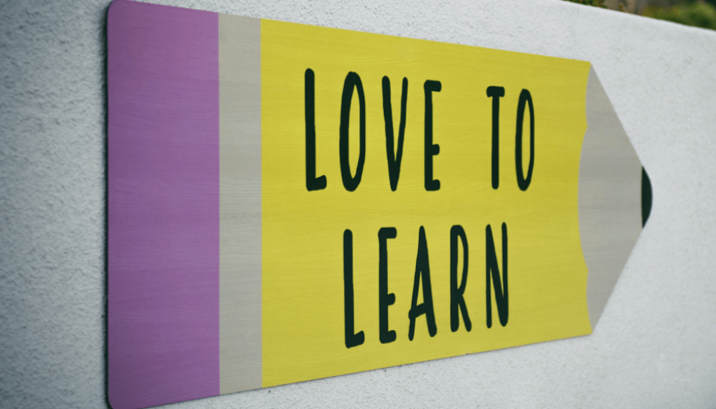 Un panneau "LOVE TO LEARN" en forme de crayon jaune